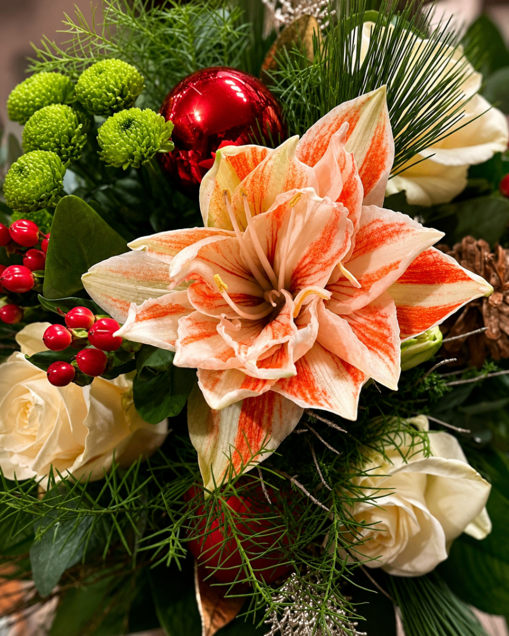 Weihnachtliches Gesteck mit Amaryllis, roten Kugeln und Tannengrün