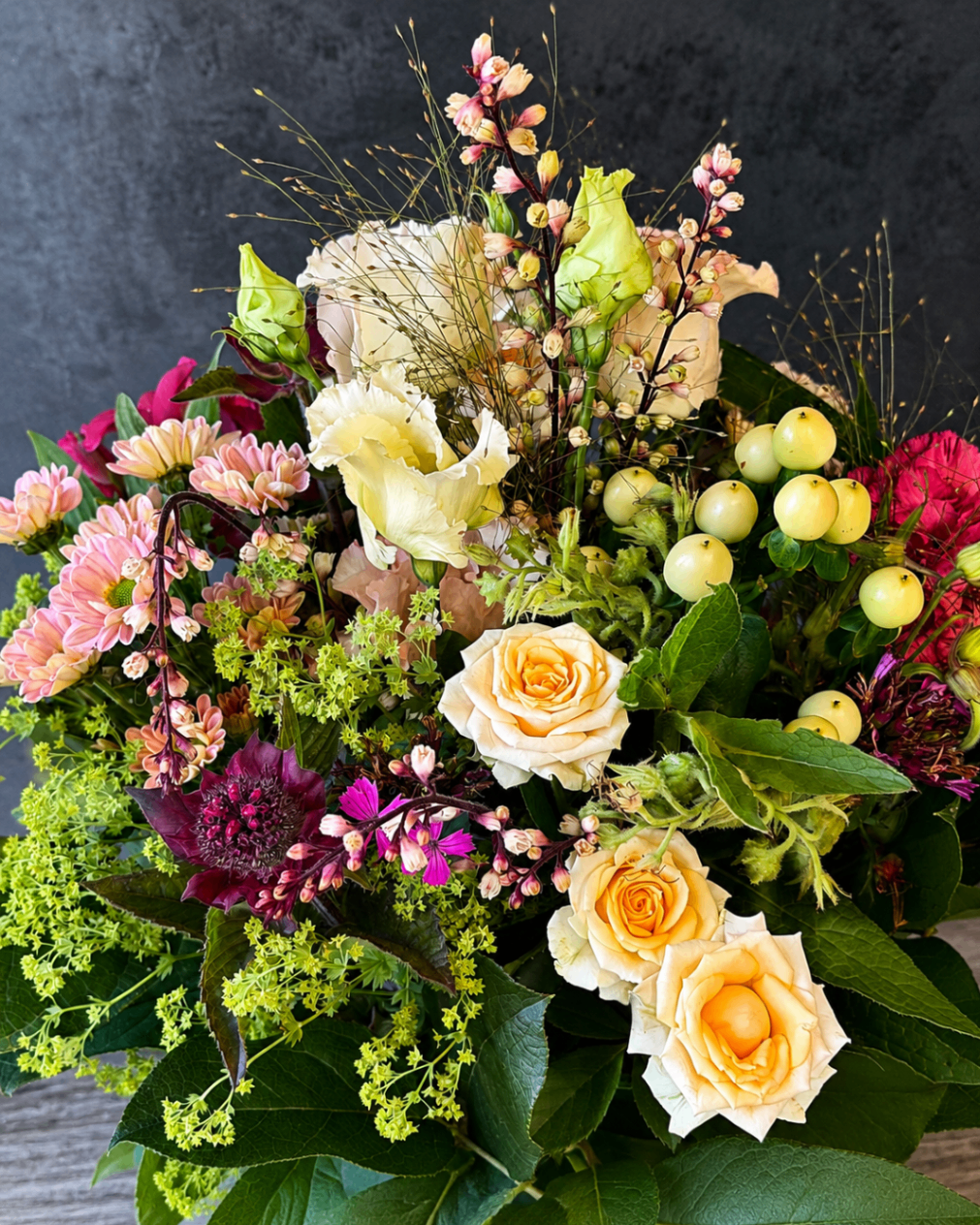 Locker gebundener, romantischer Strauß mit cremefarbenen Rosen und Beeren