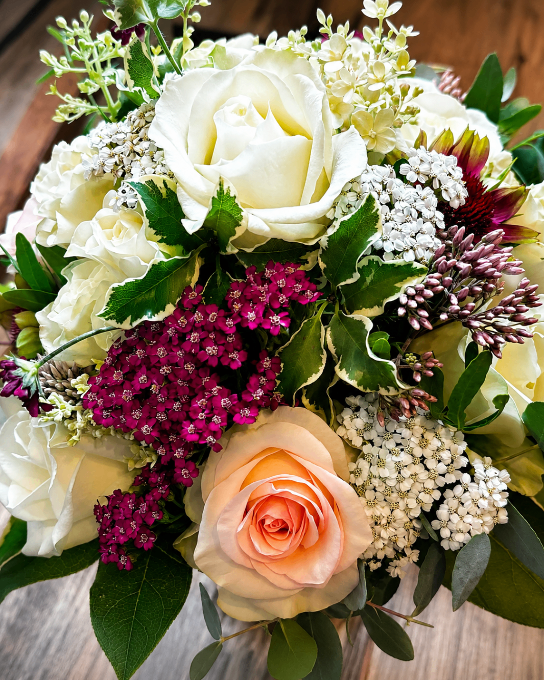 Detailreicher Strauß mit weißen Rosen, pfirsichfarbener Rose und dunkelpinken Blüten