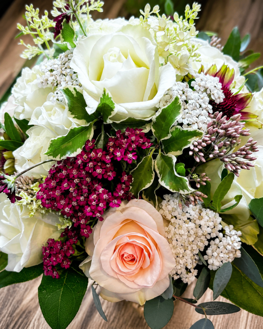 Detailreicher Strauß mit weißen Rosen, zartrosa Rose und dunkelpinken Blüten