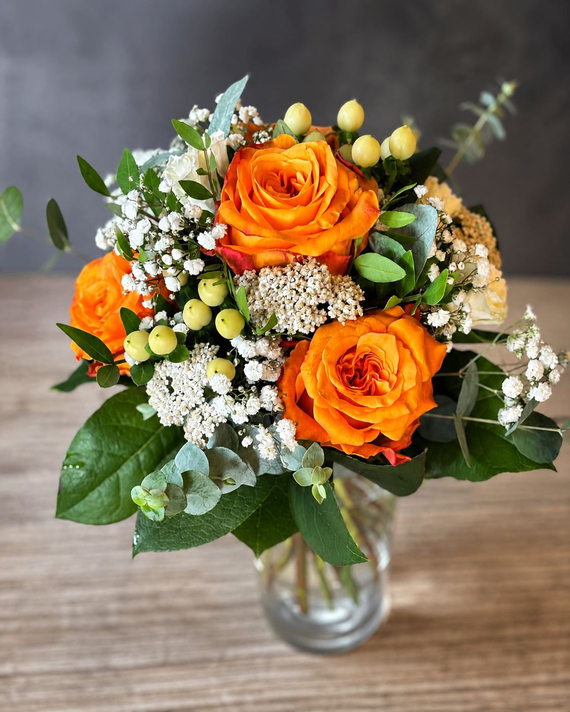Strauß mit leuchtend orangefarbenen Rosen und hellem Beiwerk