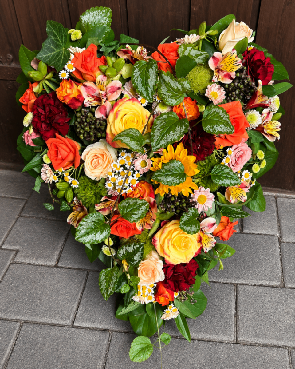 Buntes Herzgesteck mit Rosen und Sonnenblume